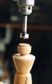 A candlestick about to be drilled on the drill press.