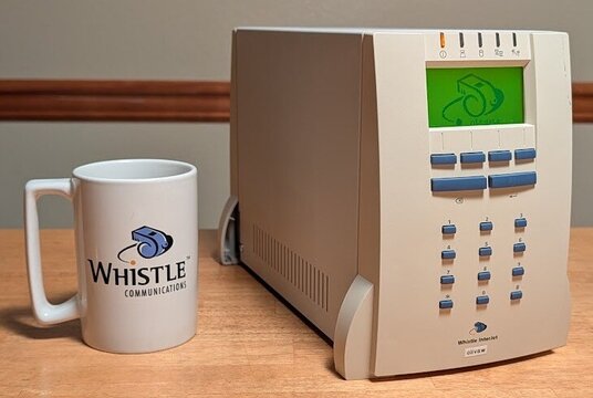 An InterJet 200 running NetBSD 11, beside an original Whistle Communications mug.