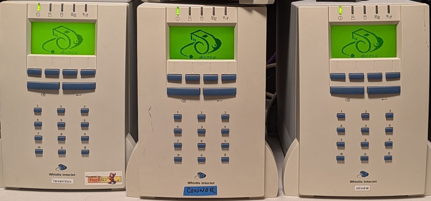 An InterJet 120 and two InterJet 200s booting NetBSD 11. The Whistle logo is drawn by our NetBSD kernel patch, not by WhistleWare; the boot stage (dhcpcd) shows beneath it.
